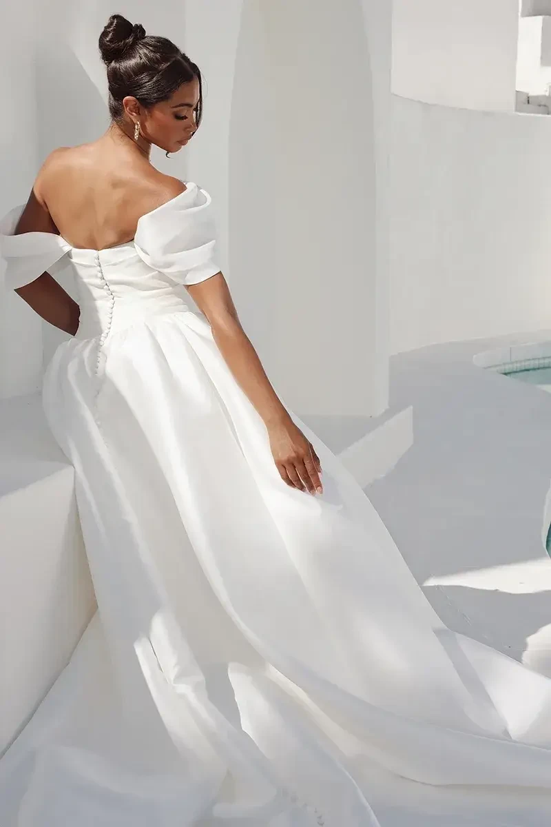 Model is wearing a silk off the shoulder a-line bridal gown