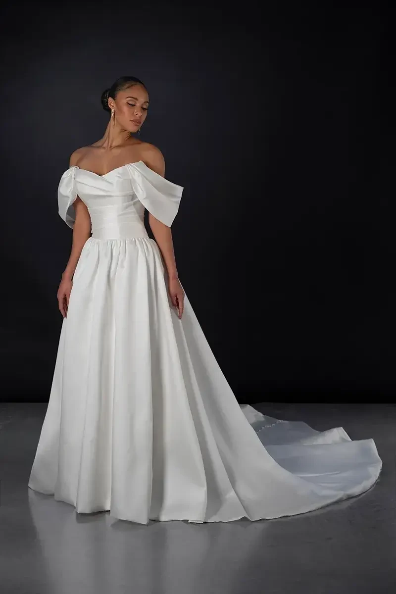 Model is wearing a silk off the shoulder a-line bridal gown
