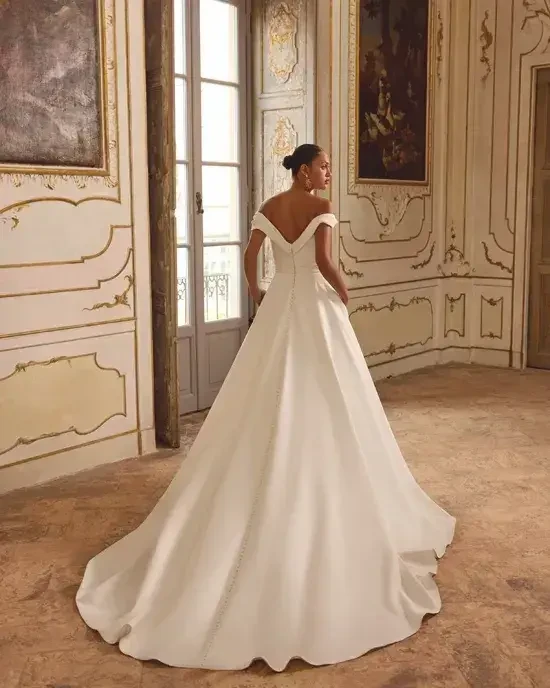model is wearing an off the shoulder a-line wedding gown