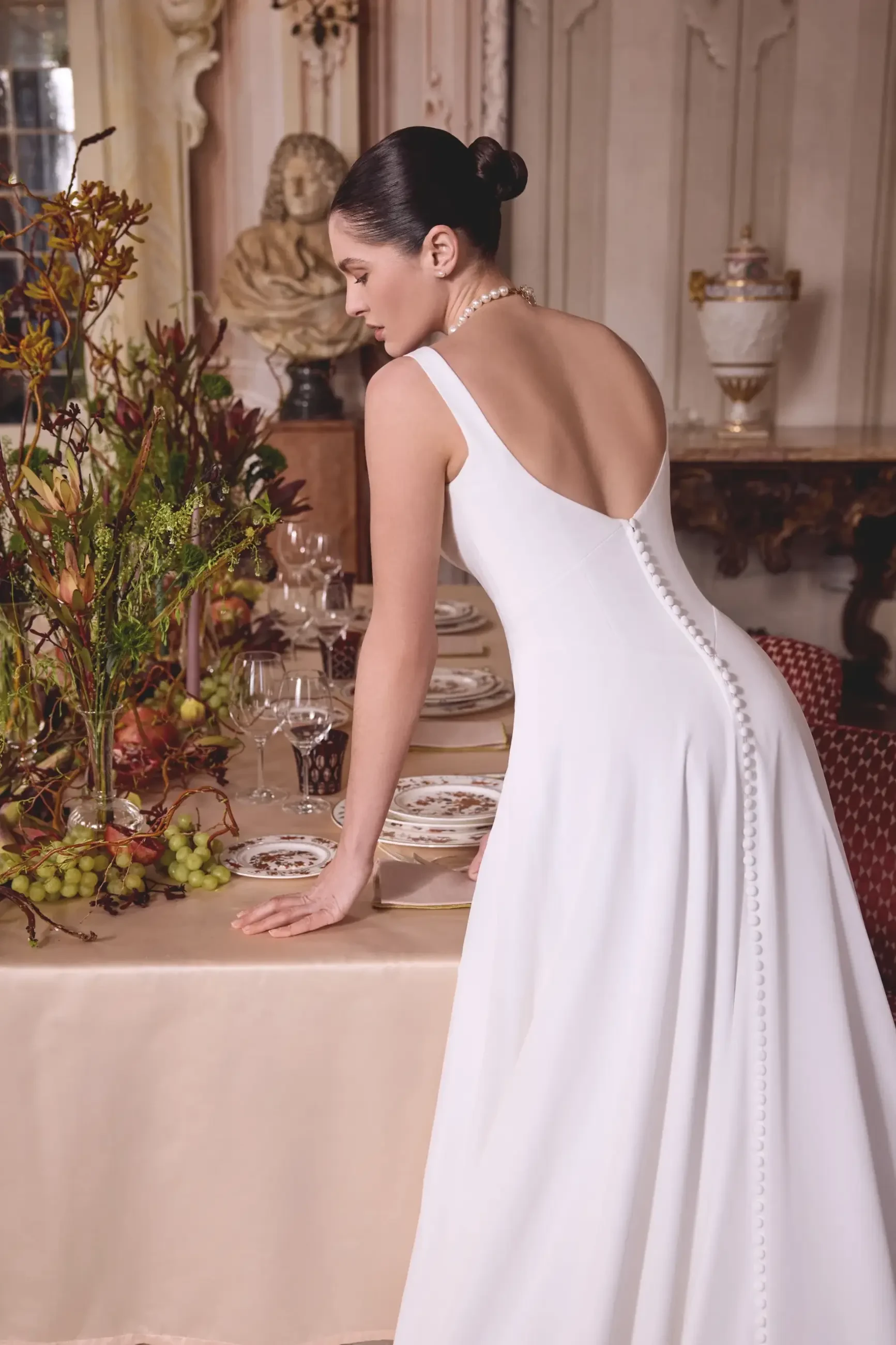 Model is wearing a sleeveless chiffon a-line wedding dress with a basque waist and sweetheart neckline