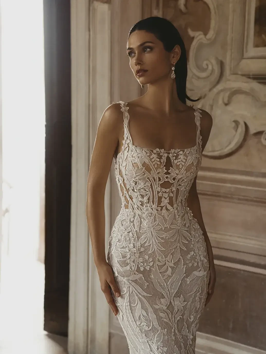 Model is wearing a fitted lace square neckline bridal gown