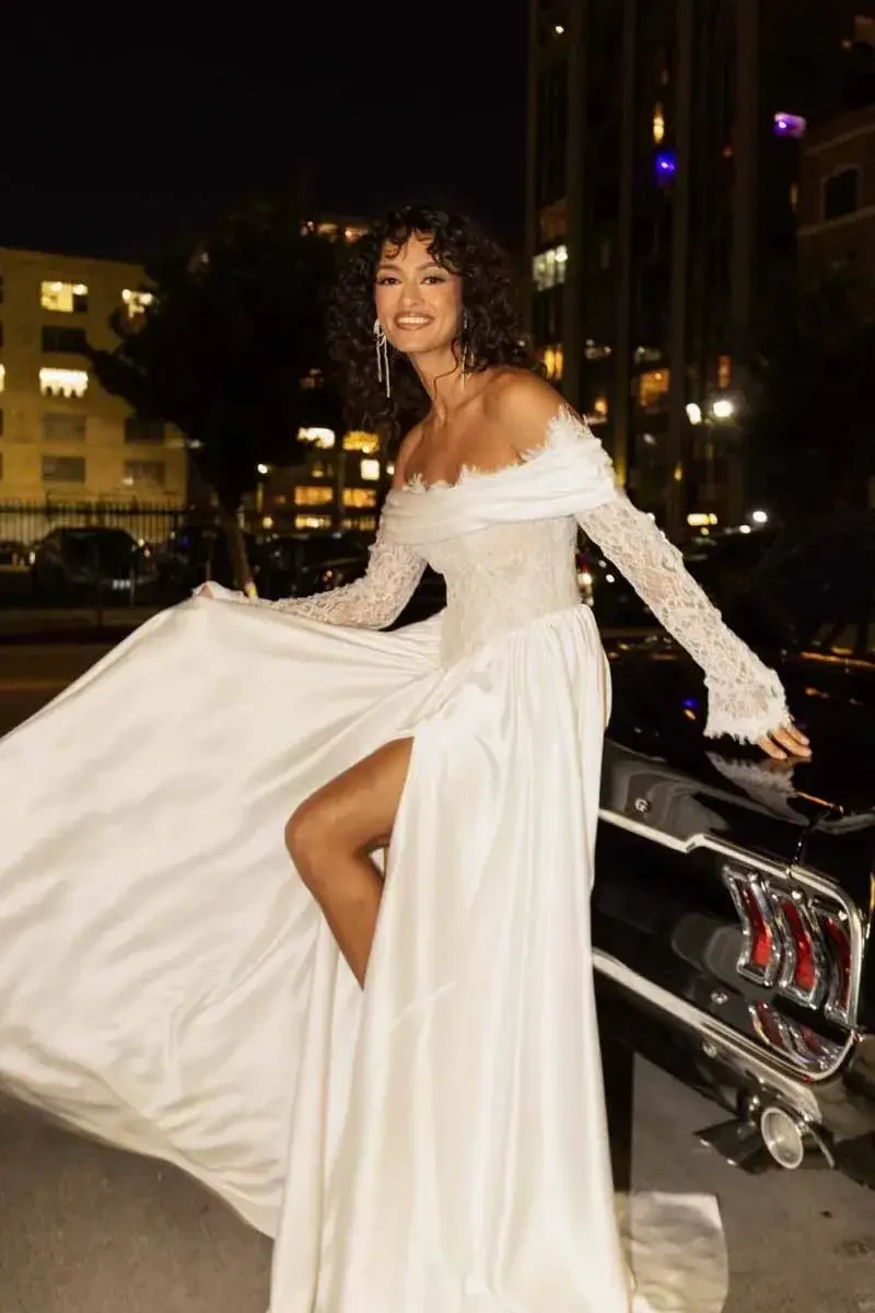 model is wearing a long sleeve off the shoulder wedding dress
