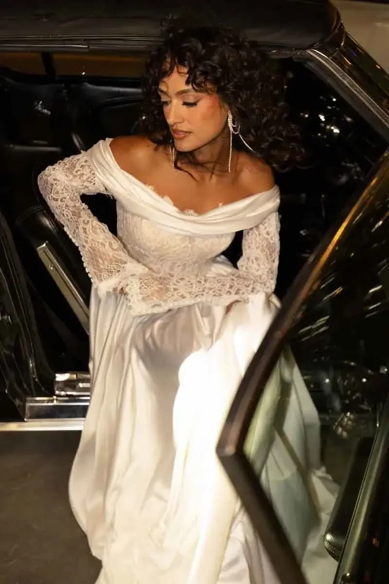 model is wearing a long sleeve off the shoulder wedding dress