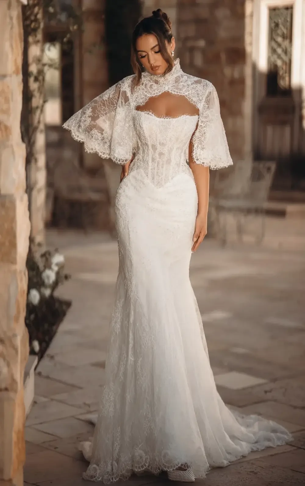 model is wearing a lace wedding dress with a lace high neck jacket
