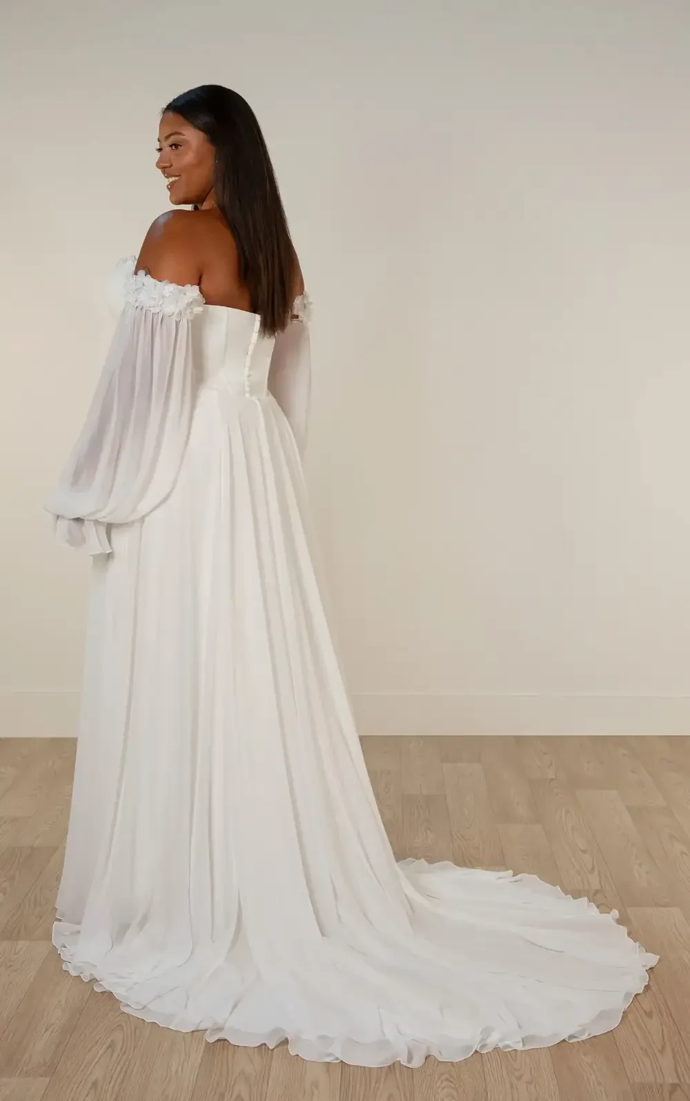 model is wearing an off the shoulder long sleeve wedding dres
