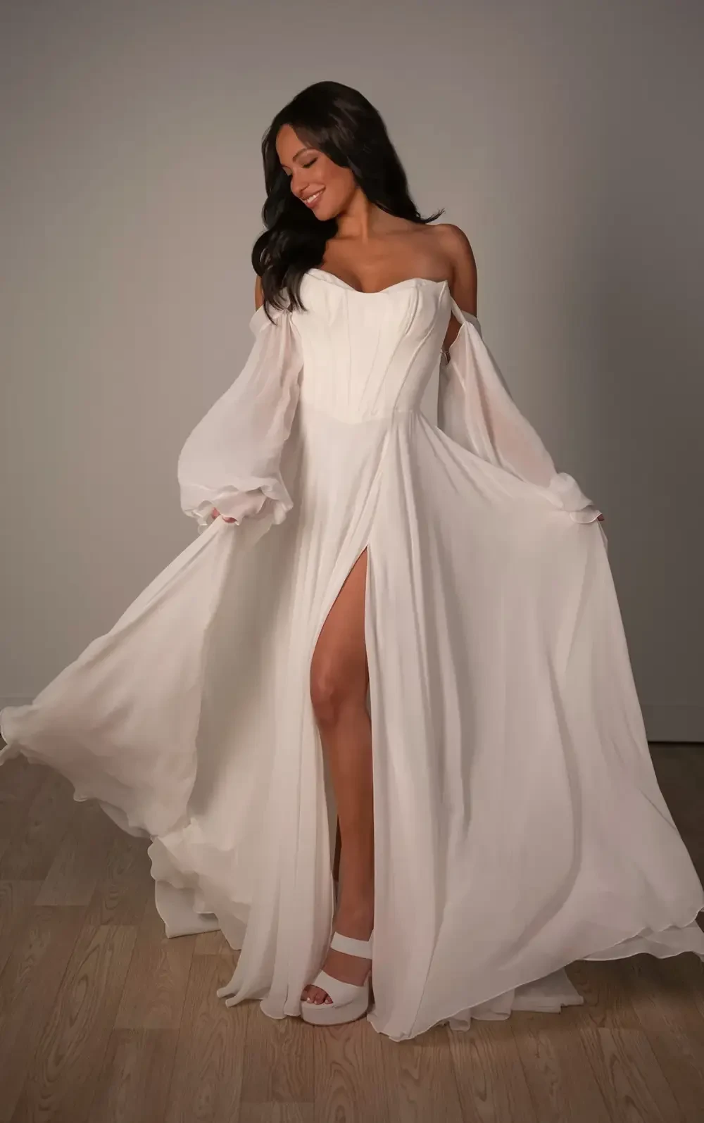 model is wearing an off the shoulder long sleeve wedding dres